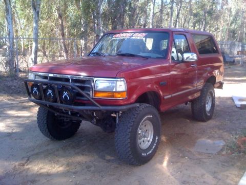 1989 Ford Bronco - This modified Ford Bronco sits outdoors with a custom bumper and large tires.