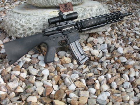 1996 Ford Bronco - Assault rifle with scope and magazine is displayed on a bed of rocks.