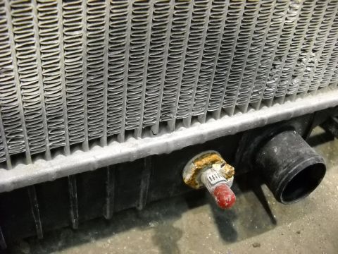 1986 Ford C-350 (Centurion Conversions) - The radiator's fins and lower tank are visible, along with a drain valve and a hose barb.