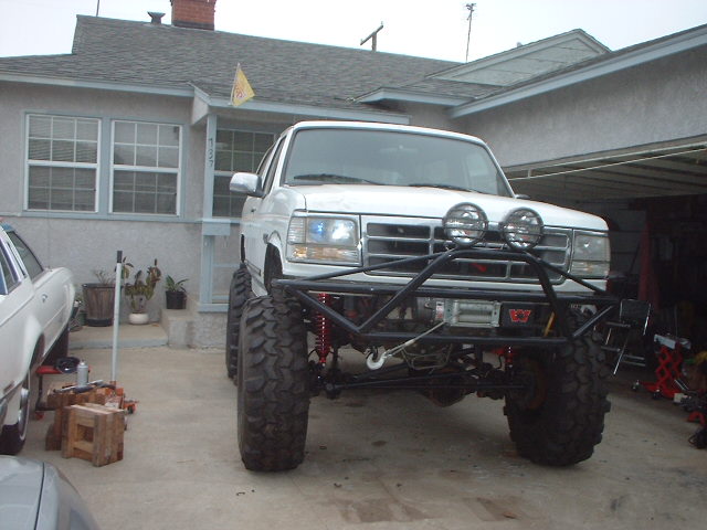 White Ford truck on extreme suspension lift with tube front bumper and winch in a driveway