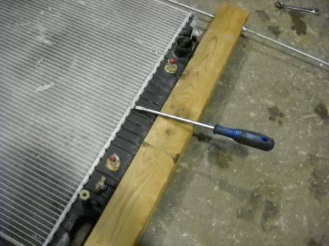 1986 Ford C-350 (Centurion Conversions) - A radiator is shown with a screwdriver and a wooden brace, likely for repair work.