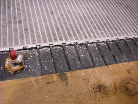 1986 Ford C-350 (Centurion Conversions) - Close-up of a vehicle radiator, showing a red cap and corroded fitting.