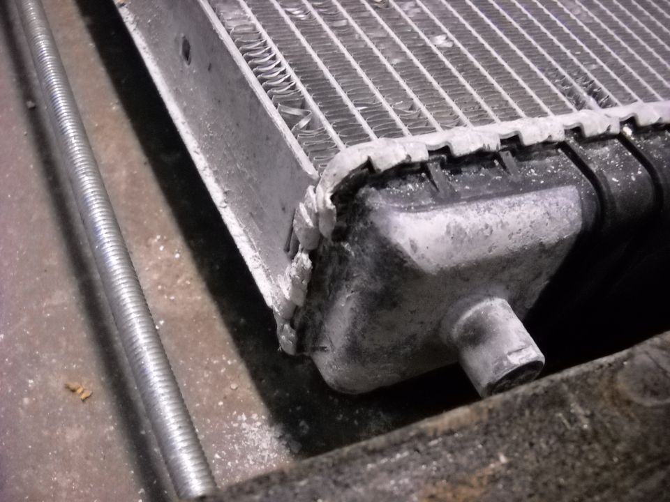 Close-up of a damaged radiator with bent fins and corroded tanks