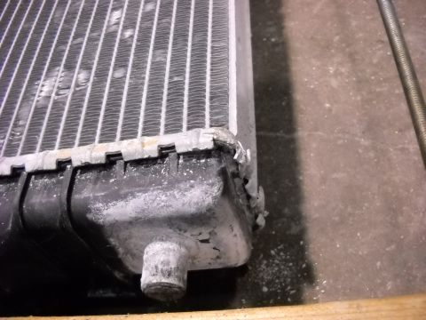 1986 Ford C-350 (Centurion Conversions) - The radiator shows signs of damage to its fins and plastic end tank, indicating a need for repair or replacement.