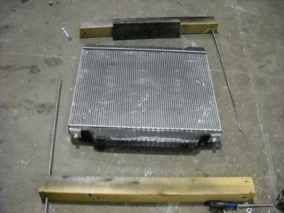 Radiator sitting on a concrete floor with wooden blocks and metal rods