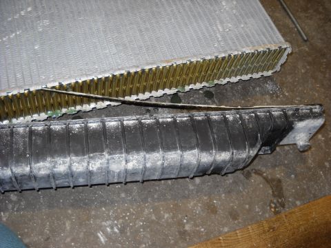 1986 Ford C-350 (Centurion Conversions) - Close-up of a damaged radiator, showing bent fins and a cracked plastic tank with white residue.