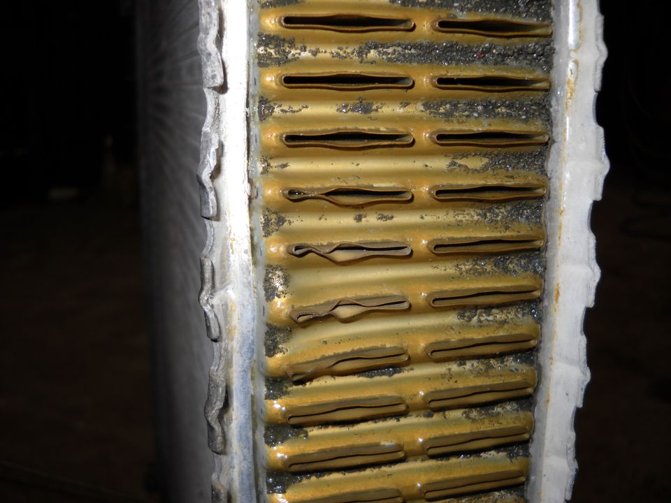 Close-up of dirty, corroded radiator fins with some bent tubes