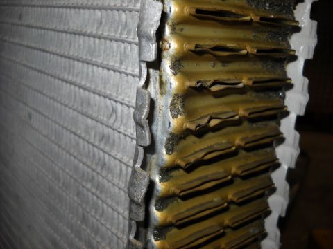 1986 Ford C-350 (Centurion Conversions) - A damaged radiator shows signs of corrosion and bent fins, indicating a need for repair.