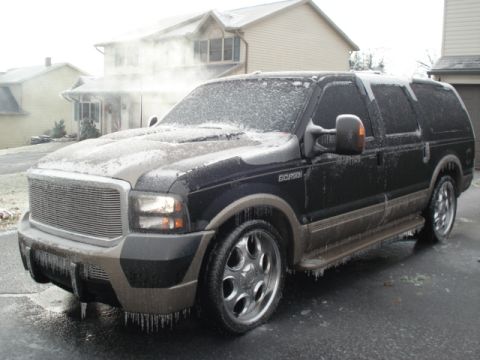 2000 Ford Excursion - A black Ford Excursion is covered in ice and icicles on a cold day, with a house in the background.
