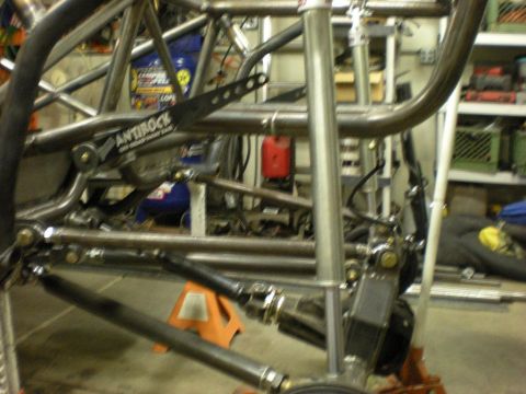 Suzuki Samurai - Bare tube chassis under construction in a shop, showing the welded roll cage, four-link suspension arms with heim joints and a black Currie…