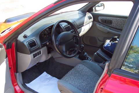 2001 Ford Crown Victoria - Interior view of a red Subaru, showing the dashboard, steering wheel, and patterned seats.