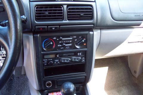 2001 Ford Crown Victoria - The interior of a car shows the center console with the radio, climate controls, and a manual transmission gear shifter.