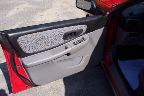 2001 Ford Crown Victoria - Interior view of a red car's driver side door panel, showing fabric and plastic trim.