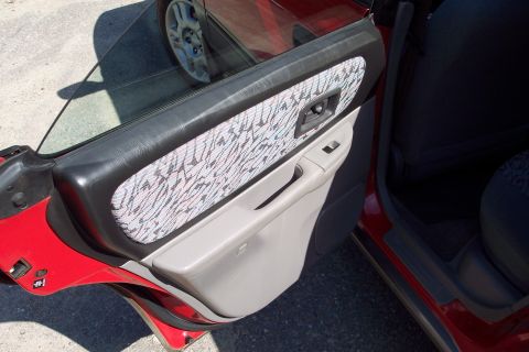 2001 Ford Crown Victoria - Interior view of a red car's front door panel, revealing fabric and plastic components.