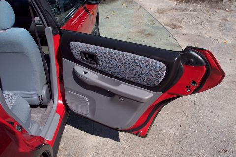 2001 Ford Crown Victoria - Interior view of a red car's door panel and seat, a patterned fabric insert and gray accents.