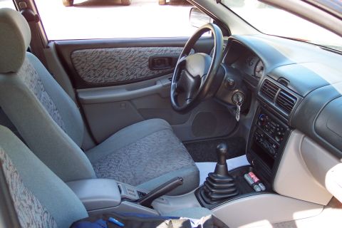 2001 Ford Crown Victoria - The interior of a car is shown, patterned fabric on the seats and door panels, a manual gear shifter, and the dashboard with instruments.