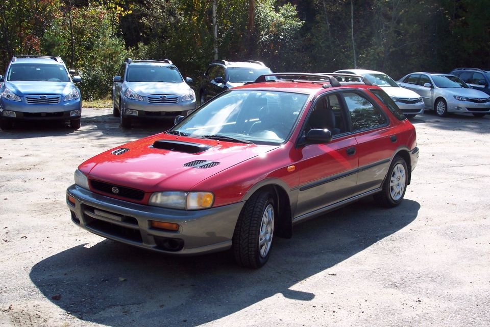 Red Subaru wagon with gray cladding parked in a lot, 3q-front view