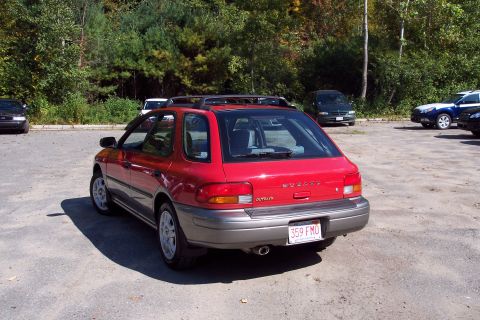 2001 Ford Crown Victoria - Rear view of a red Subaru Outback Sport wagon with a roof rack, parked outdoors.