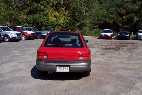 2001 Ford Crown Victoria - A red Subaru Outback is parked in a lot with other vehicles under a tree line.