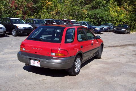 2001 Ford Crown Victoria - A red Subaru Impreza Outback Sport wagon is parked in a lot with several other vehicles visible in the background.