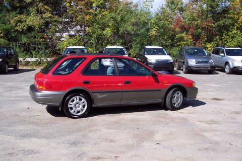 2001 Ford Crown Victoria - A red and gray Subaru Impreza Outback Sport wagon is parked in a lot with other vehicles visible in the background.