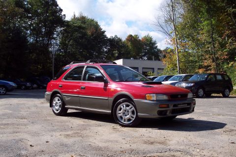 2001 Ford Crown Victoria - A red Subaru Impreza Outback Sport wagon is parked in a lot with other vehicles visible behind it.