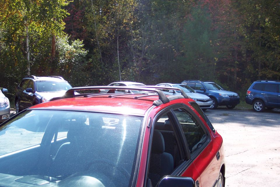 Red Subaru Outback Sport with roof rack, parked outdoors