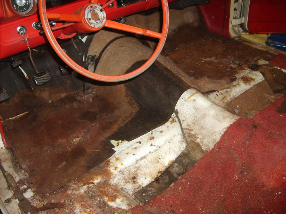 Red classic car interior floor with rust and old jute padding exposed