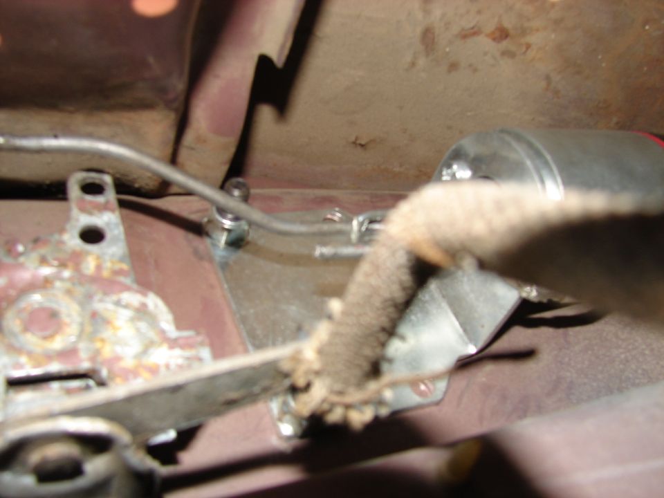 Close-up of a metal bracket and cable assembly, possibly part of a vehicle's undercarriage