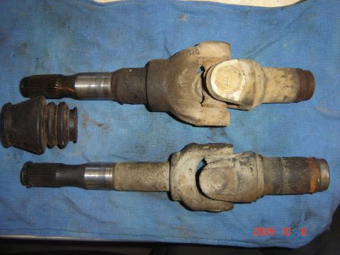 1993 Ford Bronco - Two used driveshafts and a rubber boot are laid out on a blue cloth.