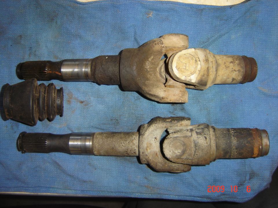 Two driveshafts and a rubber boot on a blue cloth