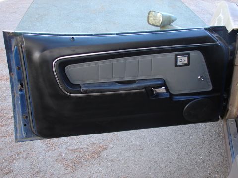 1973 Ford Ranchero - The interior door panel of a 1973 Ford Ranchero features a gray insert with horizontal stitching and black trim.