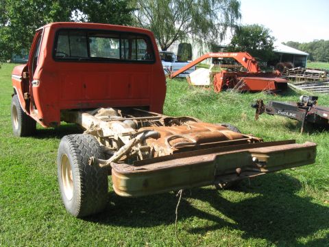 1979 Ford F-100 - The rear section of a red pickup truck is visible, showing its chassis and flatbed. The truck appears to be a donor vehicle.