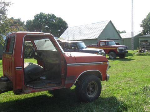 1979 Ford F-100 - Side view of a red pickup truck cab, likely a 1970s Ford, with another vehicle visible behind it.