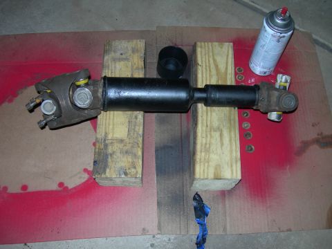 1991 Jeep Wrangler - A driveshaft assembly is shown resting on wooden blocks, with a can of spray paint nearby.