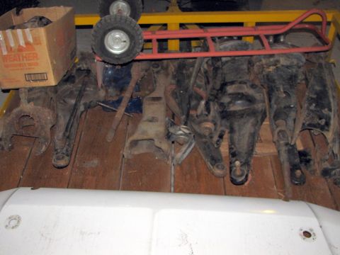 1984 Ford Bronco - Various suspension components are piled on a trailer, with a box and wheels visible.