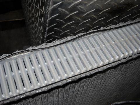 1986 Ford C-350 (Centurion Conversions) - Close-up view of a vehicle's radiator and adjacent diamond plate metal, likely in an engine bay or service area.