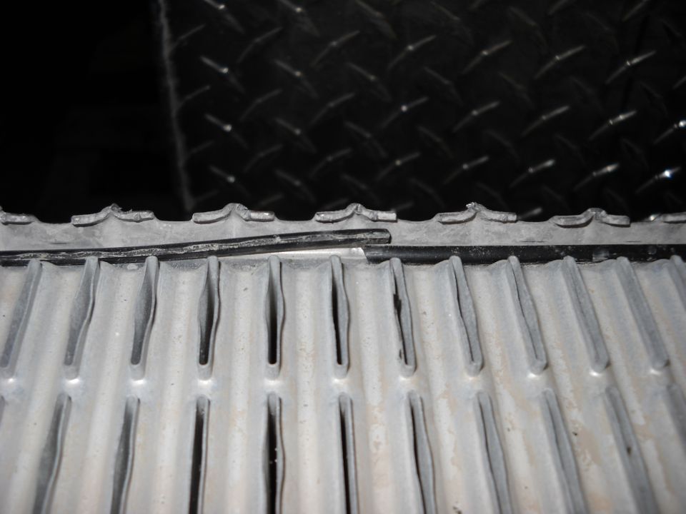 Close-up of damaged radiator fins with a black diamond plate background