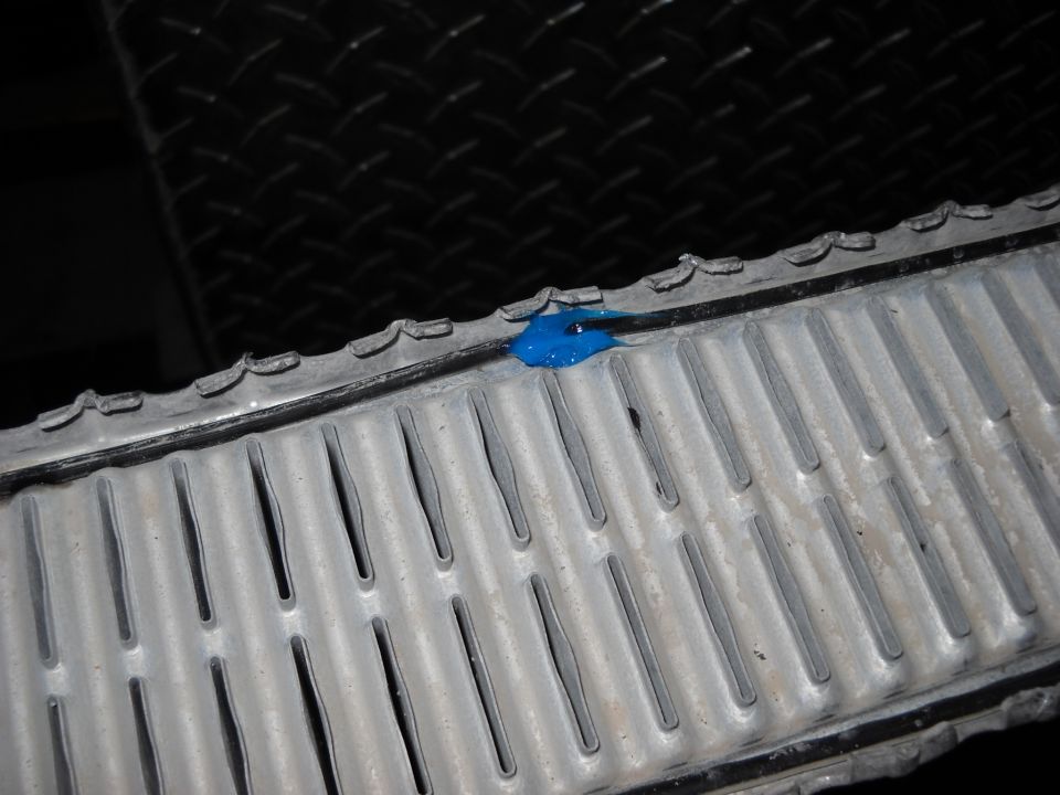 Close-up of a radiator with a blob of blue sealant on top