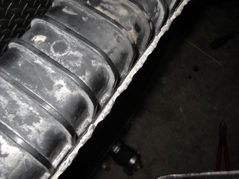 1986 Ford C-350 (Centurion Conversions) - A damaged radiator hose shows signs of wear and tear, with white residue along its ribbed surface.