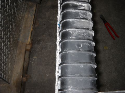 1986 Ford C-350 (Centurion Conversions) - Close-up of a radiator part, showing some text and a pair of red wire cutters on the floor.