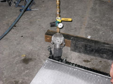 1986 Ford C-350 (Centurion Conversions) - A radiator is being pressure tested with specialized equipment including a gauge and valve.