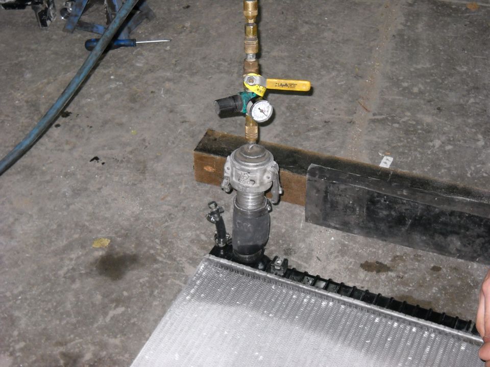 Radiator pressure tester setup with gauge, valve, and regulator attached to a radiator