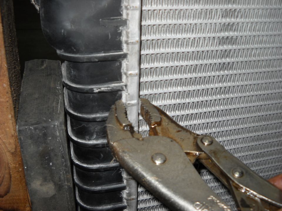 Locking pliers clamped on the crimped tank flange of an aluminum radiator core