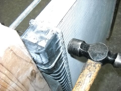 1986 Ford C-350 (Centurion Conversions) - A hammer is used to work on a vehicle's radiator, likely for repair or adjustment.