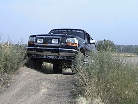 1995 Ford Bronco - This 1995 Ford Bronco is captured in a three-quarter front view as it navigates an off-road dirt path.