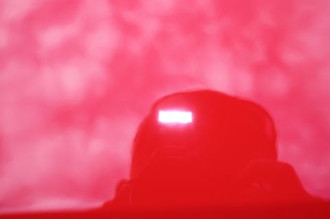 2004 Ford Mustang - A bright light reflects off the glossy red paint of a vehicle.