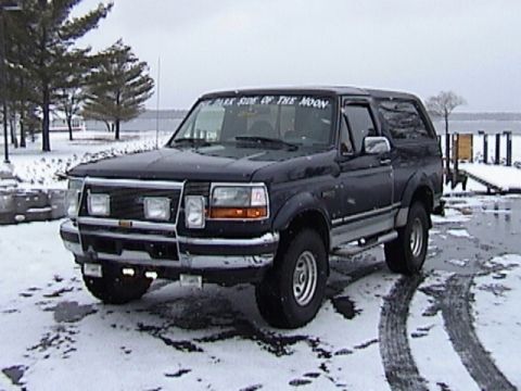 1995 Ford Bronco - A dark blue Ford Bronco is parked in a snowy area near a body of water.