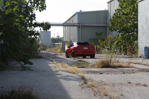 2004 Ford Mustang - Red 2004 Ford Mustang coupe seen from the rear on an abandoned industrial lot.