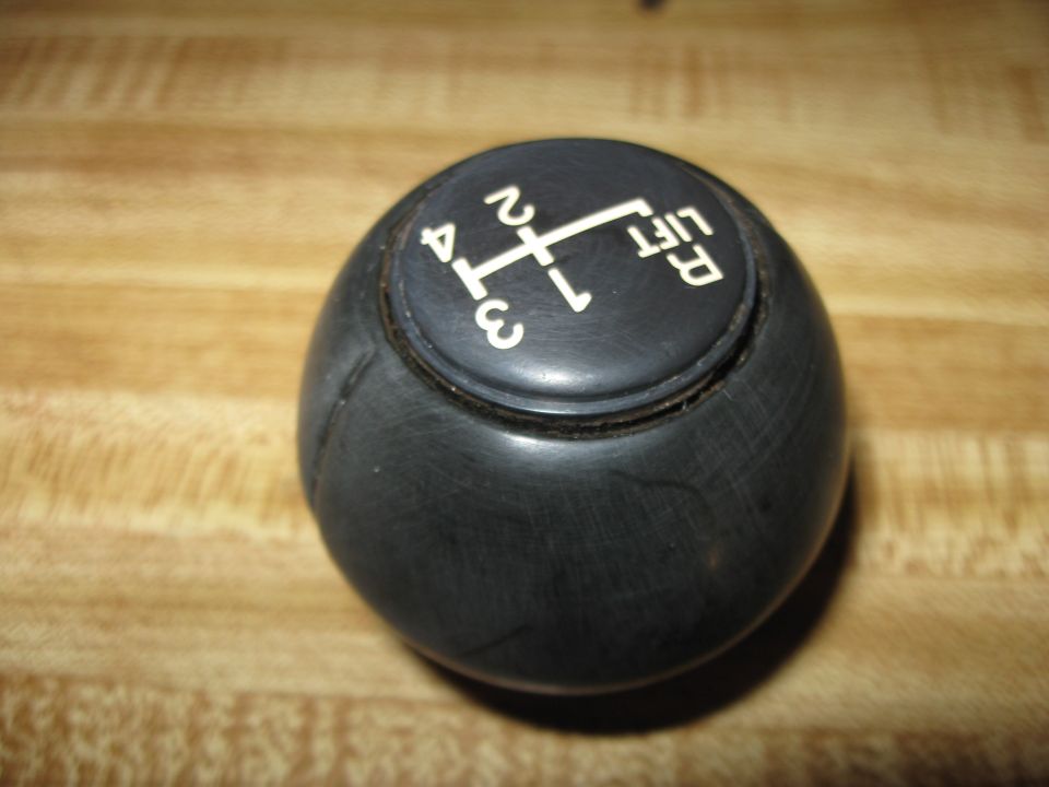 Black gear shift knob with white markings for R, 1, 2, 3, and 4